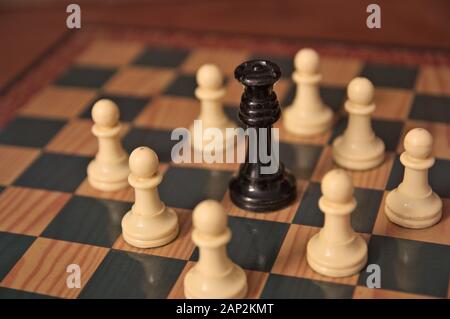 White pawns manage to surround the black king on the chess board by checkmaking in a fictional game Stock Photo