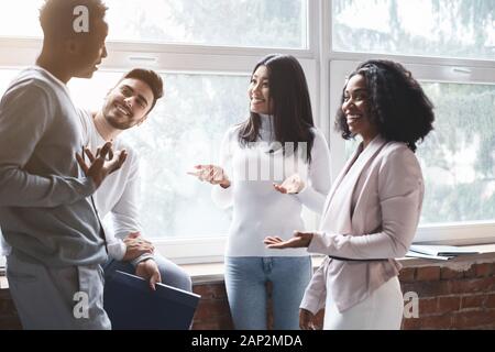 Cheerful multiracial colleagues having small talk in office Stock Photo