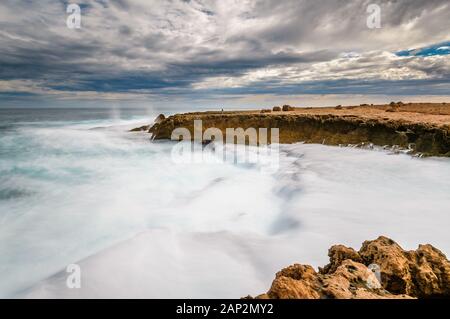 A lone tourist walker on the cliff face in a long exposure capture of the rough waters on the rugged Indian Ocean coastline at Quobba Station in W.A. Stock Photo