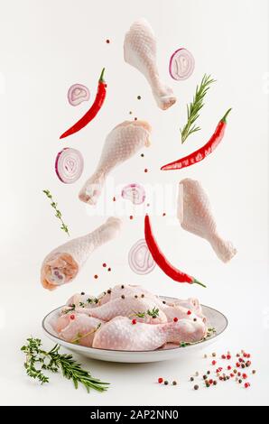 Spicy marinated raw chicken legs or drumsticks levitation. Flying food concept. Stock Photo