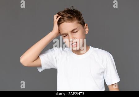 Teen boy suffering from strong headache, touching his head Stock Photo