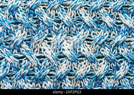 Blue and white texture of a knitted woolen fabric with a patterned weave. Sweater background Stock Photo