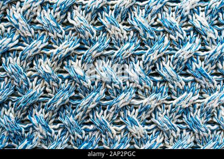 Blue and white texture of a knitted woolen fabric with a patterned weave. Sweater background Stock Photo