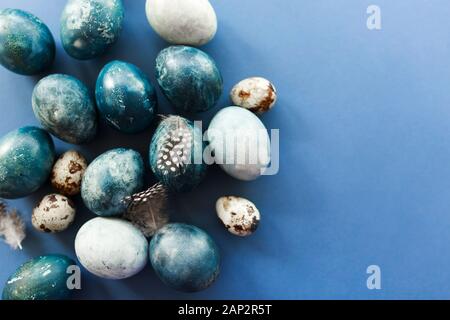 Beautiful group ombre blue Easter eggs with quail eggs and feathers on a blue background. Easter concept Stock Photo