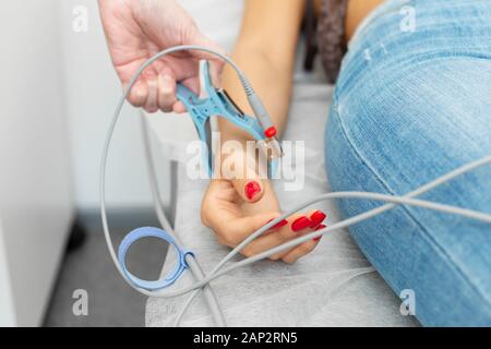 The doctor attaches the electrodes of the ECG pegs to the patient wrist. Stock Photo