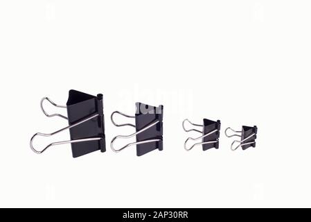 Set of four paper clip isolated on white close-up of paper clips of black color, of different sizes, from large to small. Isolated on a white backgrou Stock Photo