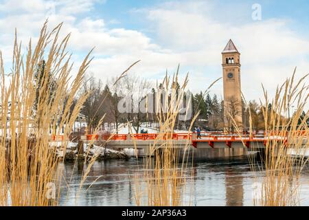 Tall reeds along the Spokane River are in focus with the river, bridge and clock tower slightly blurred behind in Riverfront Park during winter. Stock Photo