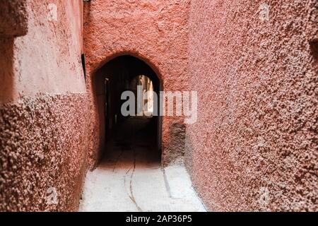 Narrow arched alley in Medina with traditional orange rose walls Stock Photo