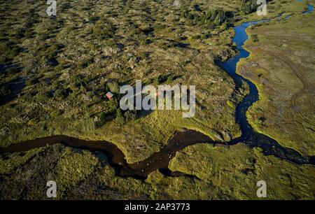From above amazing landscape of winding shallow river crossing meadow with green lush grass and woodlands Stock Photo