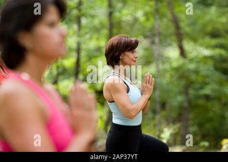 Middle aged women doing yoga in forest Stock Photo