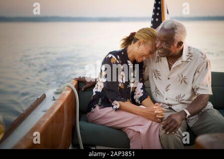 Mature adult couple embracing as they sit on a boat. Stock Photo