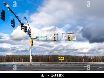 Traffic light pole with many traffic lights for different directions of traffic at the intersection with an arrow navigating the permitted direction o Stock Photo