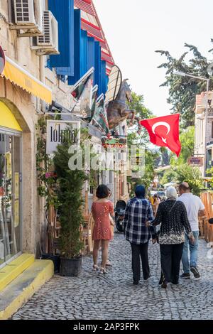 Alacati, Turkey - September 4th 2019: Tourists walking down a narrow street,. The town is a popular tourist destination. Stock Photo