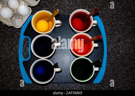 Dying Easter eggs with coffee cups and spoons from a overhead view Stock Photo