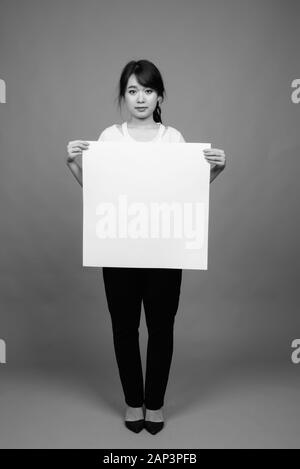 Portrait of young beautiful Asian businesswoman holding whiteboard Stock Photo