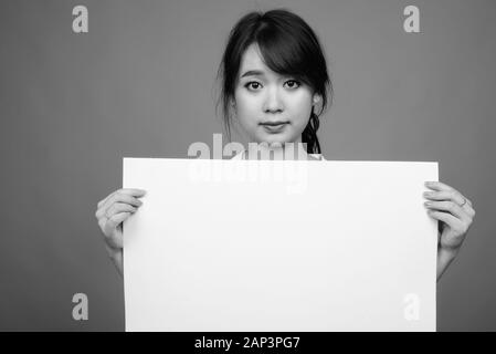 Portrait of young beautiful Asian businesswoman holding whiteboard Stock Photo