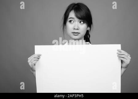 Portrait of young beautiful Asian businesswoman holding whiteboard Stock Photo