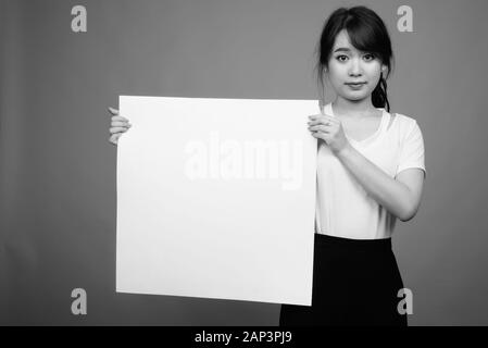 Portrait of young beautiful Asian businesswoman holding whiteboard Stock Photo