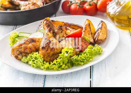 Roasted chicken legs with lettuce salad and tomatoes Stock Photo