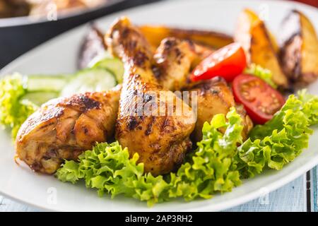 Roasted chicken legs with lettuce salad and tomatoes Stock Photo