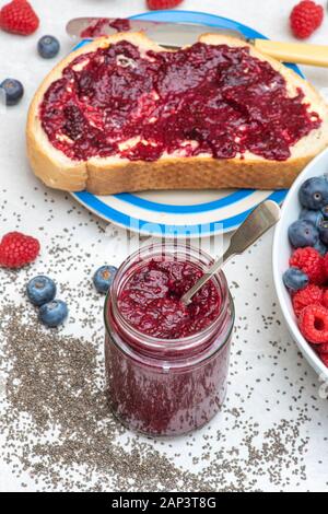 Jar of homemade chia seed berry jam with bread, fruit and chia seeds Stock Photo