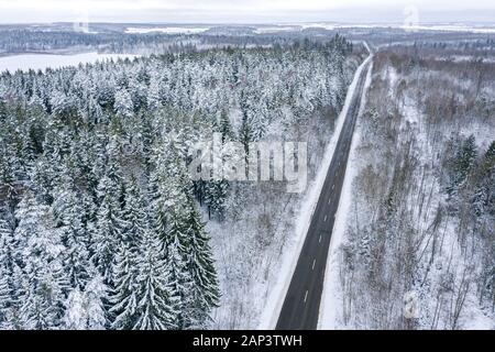 panoramic aerial view of countryside with road, fields and forest under white snow