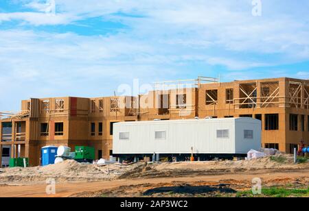 Large construction site half constructed wooden building with mobile job location office trailer in front area for contractors, work managers and supe Stock Photo