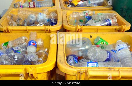 Yellow refuse bins, full to the top with used, empty single use plastic bottles which are waiting to be recycled Stock Photo