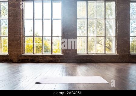 Rolled yoga pilates rubber mat inside gym studio on wooden floor background Stock Photo