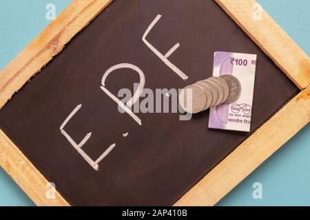 EPF or Employee provident Fund written on black slate with Indian Currency notes and Coin Stock Photo