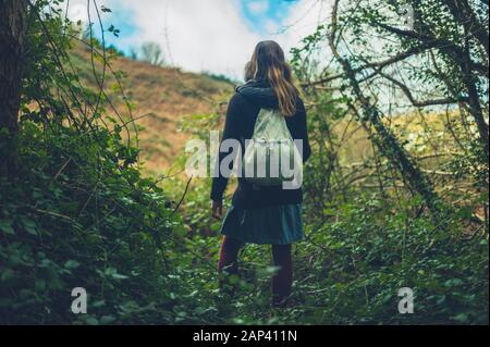 A young woman is standing in a field on the edge of woodlands Stock Photo
