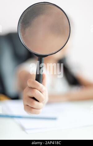 Little Asian girl using magnifier doing homework for education concept select focus shallow depth of field Stock Photo