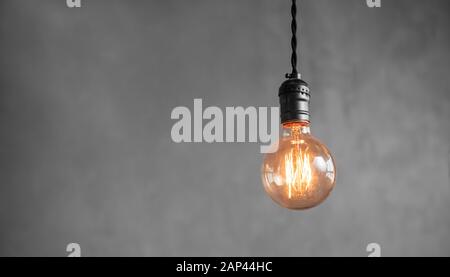 Edison retro lamp incandescent bulbs on gray plaster wall background in loft. Concept Vintage style. Copy space Stock Photo