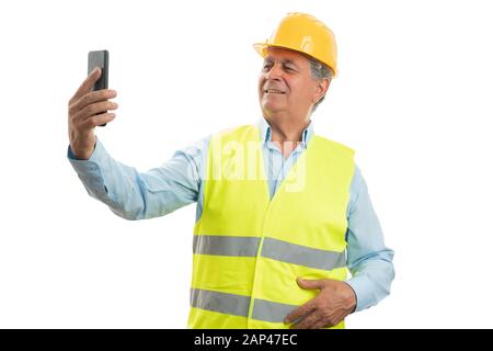 Old builder man smiling as taking selfie with smartphone isolated on white studio background Stock Photo