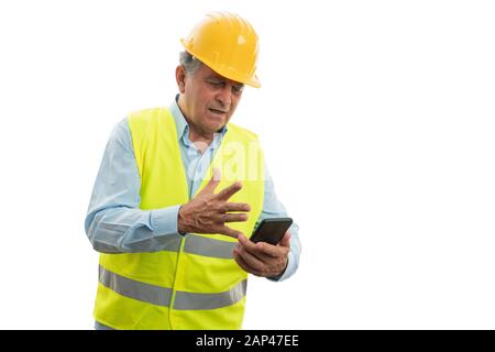 Old builder man looking at smartphone with angry expression as video call concept isolated on white background Stock Photo