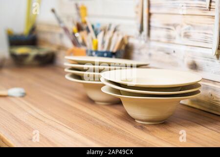 Plates and tools on pottery studio table, shallow debt of field, small art business concept Stock Photo