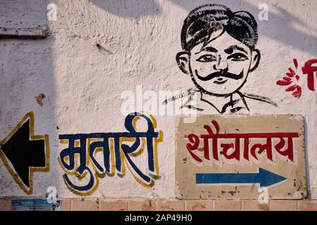 A painting on the wall on a men's toilet in Mumbai, India, pointing to the urinal on the left, and the toilet for 'bigger business' on the right Stock Photo