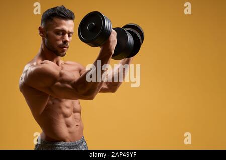 Premium Photo  Young male bodybuilder doing heavy weight exercise with  dumbbells against dark background