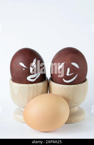 Painted and raw eggs. Funny drawings on eggshells. Easter artistic decoration. Stock Photo