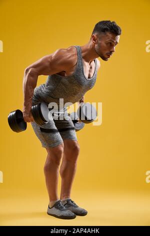 Male Bodybuilder Side View Rows Side view of a bodybuilder doing heavy weight workout for biceps Stock ...