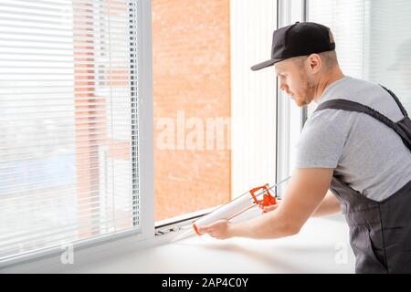 Construction worker use gun silicone tube for repairing and installing window in house Stock Photo