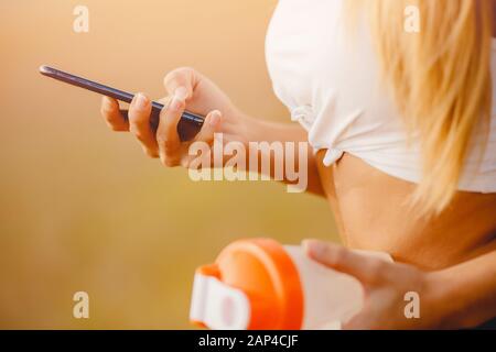 Beautiful blonde girl chooses music playlist for running in park Stock Photo