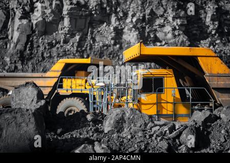 Big yellow mining truck laden anthracite moves open pit coal mine Stock Photo