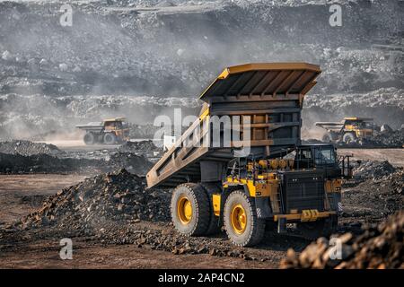 Big yellow mining truck laden anthracite moves open pit coal mine Stock Photo