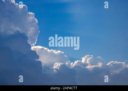 Background of rays of the sun breaking through the clouds in the blue sky Stock Photo