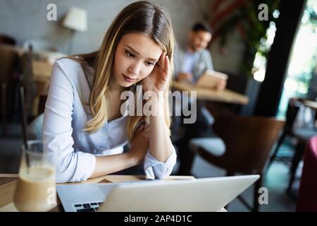 Portrait of tired young business woman with laptop Stock Photo
