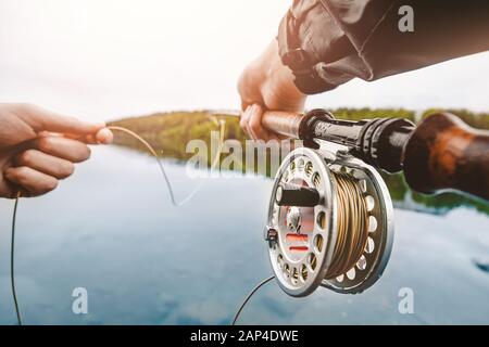 Coil of fly fishing rope, man hands holding rod Stock Photo