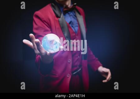 Oracle shows future in ball hands with magic glow on black background Stock Photo