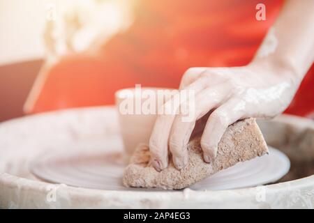 Top view of the potter wheel, hands of young woman make ceramic dishes from clay Stock Photo