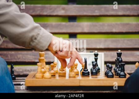 Elderly man senior holds chess piece game board outdoors Stock Photo
